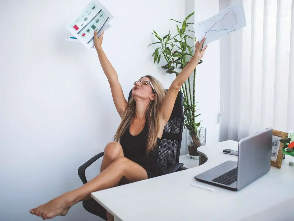 Persona celebrando con gráficos y resultados impresos en una oficina, representando el logro al finalizar el análisis cuantitativo en un proyecto académico